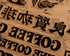 A close up of block print hand carved into wood with the word 'coffee' visible.