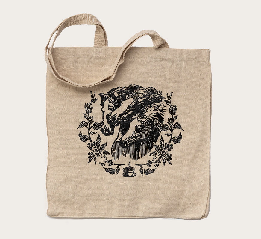Canvas tote bag with a black printed horse surrounded by floral art on the front side.