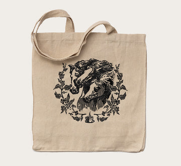 Canvas tote bag with a black printed horse surrounded by floral art on the front side.